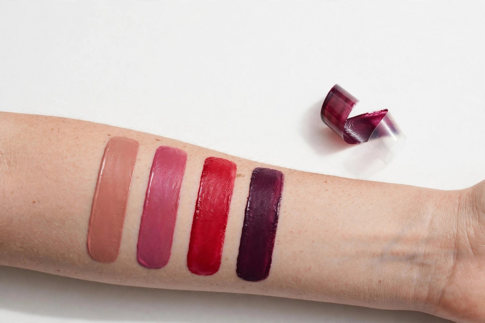 Peel-off lip stain shade swatches in nude rose, berry, red and plum